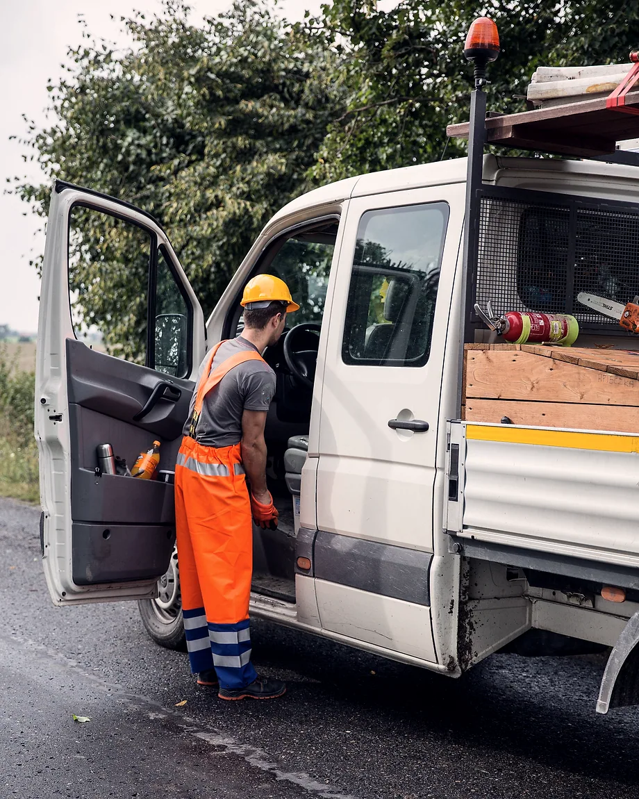 A tradesman loading tools into the side door of his work van on a quiet road.